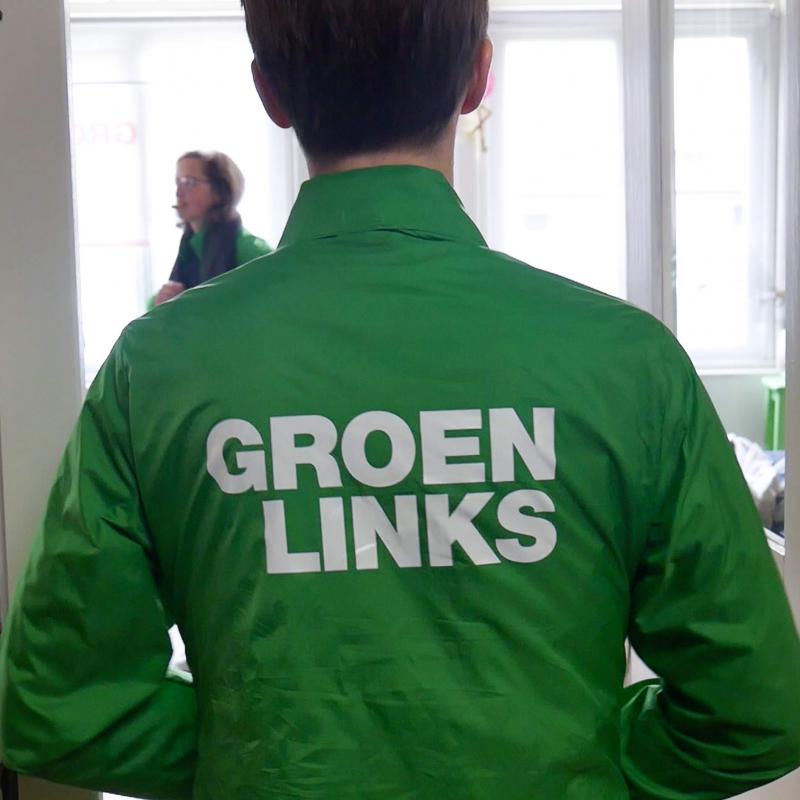 Een GroenLinks-vrijwilliger met een groene campagnejas aan